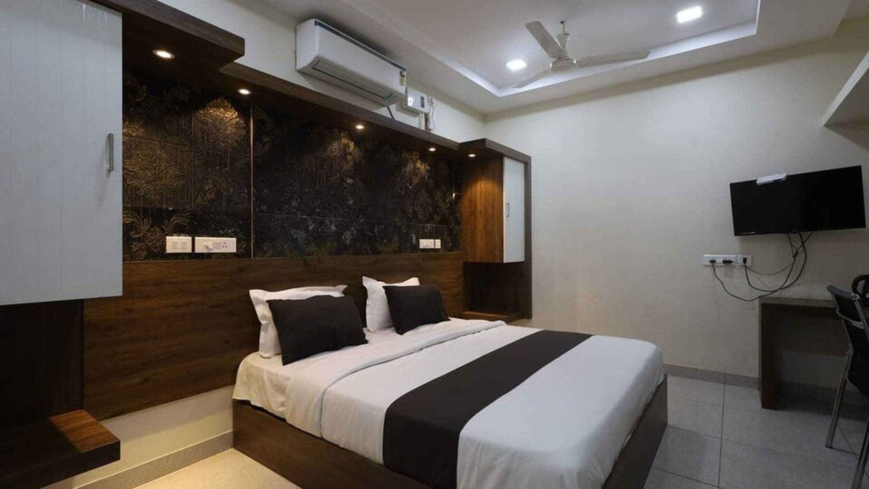 Un dormitorio moderno con una cama, un televisor de pantalla plana y un equipo de aire acondicionado.