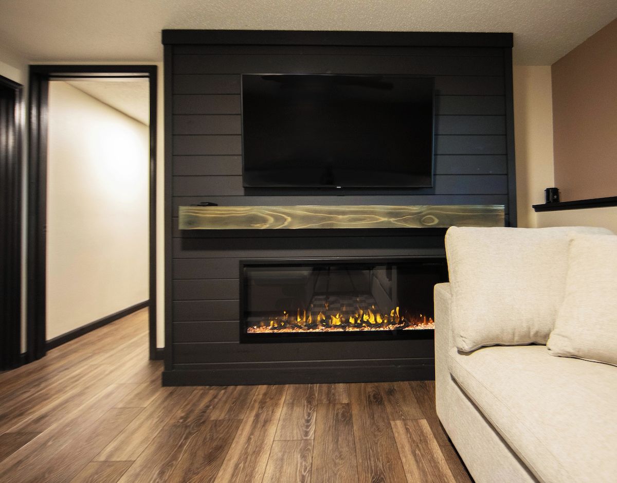 A modern living room with a fireplace, a television mounted above it, and a sofa.