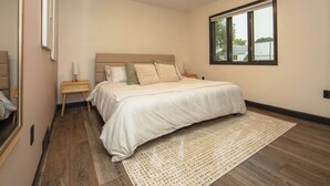 A bedroom with a large bed, a nightstand, a bedside lamp, and a window with a view. - New Listing: Freshly updated and blocks from campus, downtown and trails (Waverly)