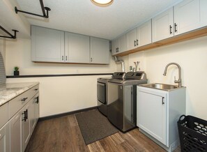 A compact kitchen with white cabinets, a stainless steel sink, and a built-in oven.
