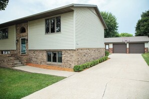 A two-story house with a brick foundation and siding, a front garage, and a driveway.