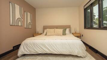 A bedroom with a large bed, a window, and wall art.