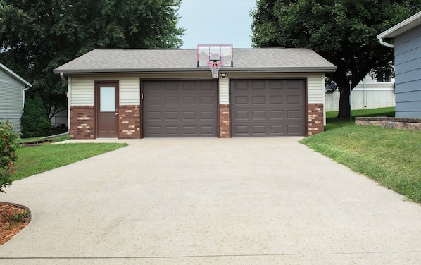 A single-story building with two garage doors, a basketball hoop, and a driveway.