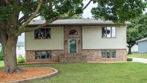A two-story house with a brick facade, a green front door, and a small front yard with a tree and mulch. - New Listing: Freshly updated and blocks from campus, downtown and trails (Waverly)