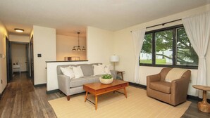 A living room with a sofa, armchair, coffee table, and a window with curtains. - New Listing: Freshly updated and blocks from campus, downtown and trails (Waverly)