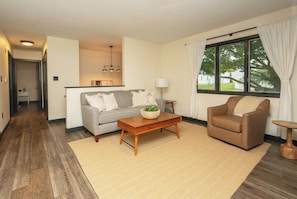 A living room with a sofa, armchair, coffee table, and a window with curtains. - New Listing: Freshly updated and blocks from campus, downtown and trails (Waverly)