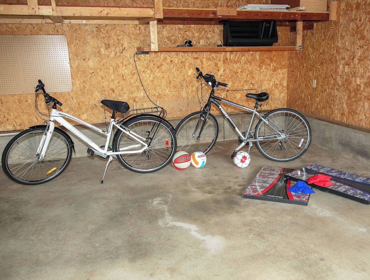 Two bicycles parked indoors with a volleyball net and balls on the floor.