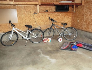 Two bicycles parked indoors with a volleyball net and balls on the floor.