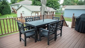 An outdoor deck with a table and chairs, a covered umbrella, and a basketball hoop. - New Listing: Freshly updated and blocks from campus, downtown and trails (Waverly)