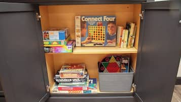 Un espace de rangement équipé d’étagères contenant divers jeux de société et casse-têtes.