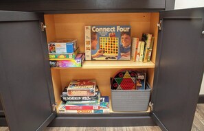 Un espace de rangement équipé d’étagères contenant divers jeux de société et casse-têtes.