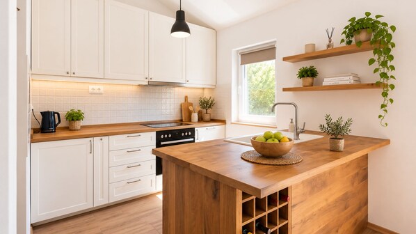 A modern kitchen with white cabinets, a wooden island, and a window providing natural light.