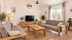 A modern living room with a sofa, a coffee table, a TV, and a clock on the wall.