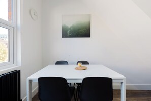 A room with a white table, black chairs, a clock, and a framed picture on the wall. - Modern 4BDR Flat in the Heart of Wandsworth (Greater London)