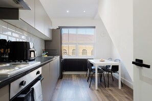 A modern kitchen with a dining area, a view of the city, and a radiator. - Modern 4BDR Flat in the Heart of Wandsworth (Greater London)