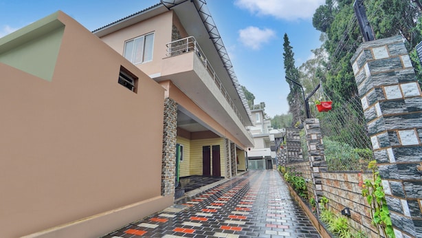 Un edificio residenziale con tetto spiovente, un balcone e un vialetto lastricato che conduce all'ingresso.