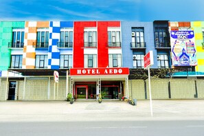 A hotel with a red sign, multiple balconies, and a colorful facade.