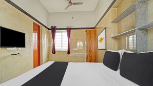 A hotel room with a bed, a flat-screen TV, a ceiling fan, and a window with curtains. - Hotel O Jaganath Nagar Near Hopes (Coimbatore)