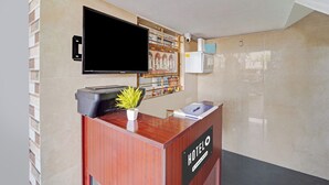 A reception desk with a flat-screen TV, a potted plant, and a sign indicating the hotel name. - Hotel O Jaganath Nagar Near Hopes (Coimbatore)