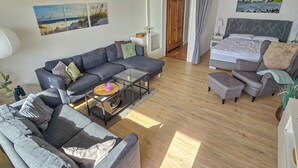 Una sala moderna con un sofá, una mesa de centro y una cama con cabecera.