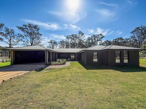 Uma casa moderna de dois andares com garagem coberta e gramado bem cuidado.