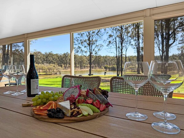 A table with a bottle of wine, glasses, and a fruit and cheese board.