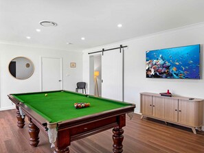 Quarto com mesa de bilhar, armário, espelho e quadro na parede.