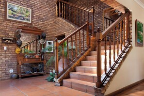 A wooden staircase with a brick wall backdrop, a welcome sign, and various decorative items including hats and a framed picture.