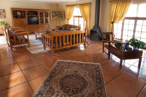 A spacious living room with a fireplace, wooden furniture, and a large rug.