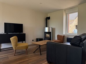 Ein modernes Wohnzimmer mit Flachbildfernseher, einer Couch, einem Couchtisch und einem Kamin.