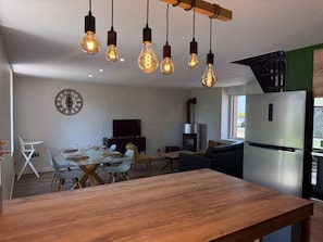 Eine moderne Küche mit einem Edelstahlkühlschrank, einem eingebauten Ofen und einem Holzespeisetisch mit Stühlen.