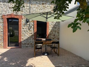 Eine Terrasse mit Tisch, Stühlen und Sonnenschirm, sowie eine Steinmauer.