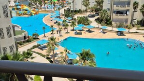 A resort with multiple swimming pools, palm trees, and a view of high-rise buildings. - Vrbo Property (Monastir)