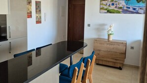 A modern kitchen with a black countertop, wooden chairs, and a wooden cabinet. - Vrbo Property (Monastir)