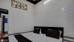 Ein Hotelzimmer mit einem großen Bett, einem Kopfteil, einer Wand mit Marmorstruktur und drei gerahmten Kunstwerken über dem Bett.
