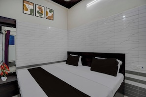 Camera d'hotel con un letto grande, una testiera, una parete con motivo marmorizzato e tre opere d'arte incorniciate sopra il letto.