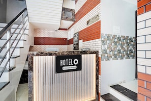 A hotel reception area with a check-in counter, reception desk, and a staircase. - Hotel O Krishna Janam Bhoomi (Mathura)