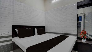 Ein modernes Schlafzimmer mit einem großen Bett, einem dunklen Kopfteil und einem Spiegel an der Wand.