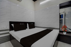 Una camera da letto moderna con un letto grande, una testiera scura e uno specchio a parete.