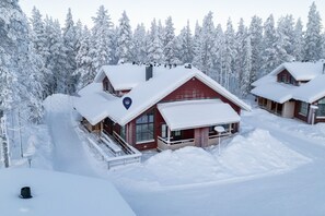 Eine schneebedeckte Lodge mit einem markanten roten Dach, umgeben von dichten Nadelbäumen.