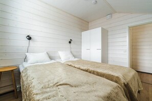 A room with two beds, a small table, a wardrobe, and a door. - SointuiLevi Superior A73 by Holiday in Lapland (Levi)