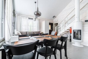 A modern interior with a dining area, a sofa, a fireplace, and a staircase. - SointuiLevi Exclusive A57 by Holiday in Lapland (Levi)