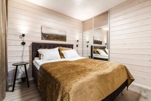 Een slaapkamer met een bed, nachtkastjes, een spiegel en een schilderij aan de muur.