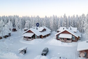 A snow-covered lodge with multiple cabins, a central blue marker, and a car parked in the foreground. - SointuiLevi Exclusive A57 by Holiday in Lapland (Levi)