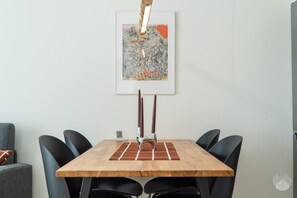 Ein Essbereich mit einem Holztisch, schwarzen Stühlen, einem gerahmten abstrakten Gemälde und einem Kerzenhalter.