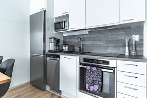 Een moderne keuken met roestvrijstalen apparatuur, een koffiezetapparaat en een magnetron.