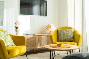 A modern living room with yellow armchairs, a round coffee table, and a wooden console table with decorative items. - Aurinkorinne 2 A by Holiday in Lapland (Levi)