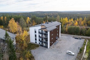 Ein modernes Gebäude mit Parkplatz und Blick auf eine bewaldete Landschaft.