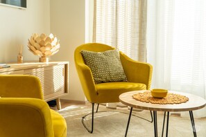 A room with a yellow armchair, a round table with a yellow bowl, and a decorative wooden object on a wooden cabinet. - Aurinkorinne 2 A by Holiday in Lapland (Levi)
