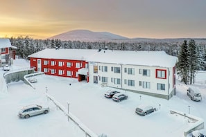 A building with multiple windows and a flat roof, surrounded by snow-covered ground and trees. - Levi Postintie 3B apart.322 by Holiday in Lapland (Levi)